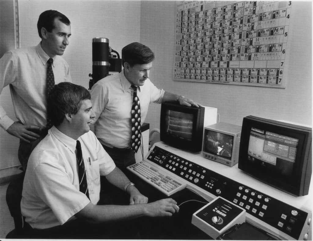 <strong>1995 R&D 100 Winners </strong>— Ed Cole, sitting, Chris Henderson, left, and Rich Anderson look at an electron microscope image produced by the charge-induced voltage alteration technique. The groundbreaking nondestructive integrated-circuit failure analysis technique earned them an R&D 100 award in 1995. (Photo by Randy Montoya)
