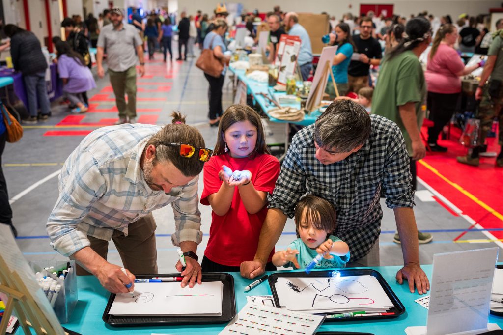 <strong>TINY BOTS </strong>— From left, Andy Graves; his daughter Rocío Sandoval-Graves, 8; her cousin Matías Sandoval, 3; and Matías’s father, Marcos Sandoval, work with small Ozobots robots to execute a line of instructions at Jefferson Middle School Science Night on April 9. (Photo by Craig Fritz)