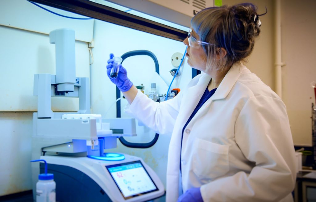 <strong>MASTER MICROWAVE</strong> — Sandia nanomaterials chemist Clare Davis-Wheeler Chin loads a sample of cathode material into a microwave reactor to open it up into tiny layers called nanosheets. (Photo by Bryn Whisenand)