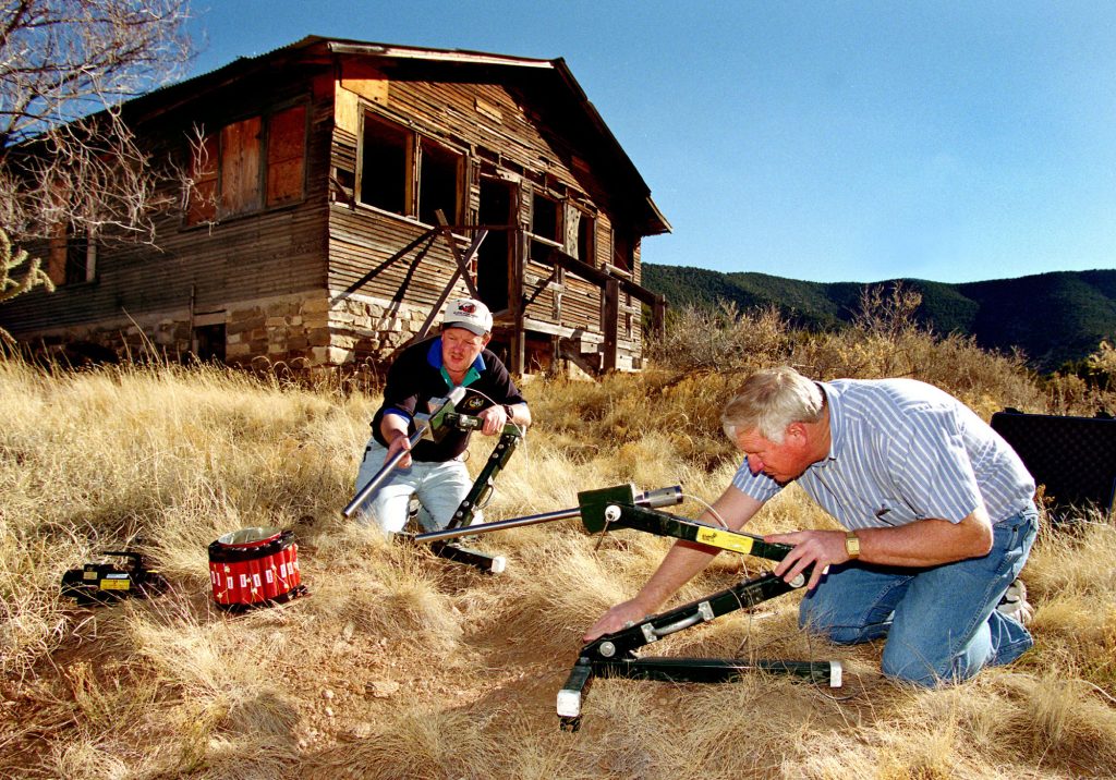 <strong>BOMB BUSTERS</strong> — Sandia bomb disablement experts Chris Cherry, right, and Rod Owenby demonstrate use of two Percussion-Actuated Non-electric Disrupters on a mock bomb in a photo from 2002. (Photo by Randy Montoya)