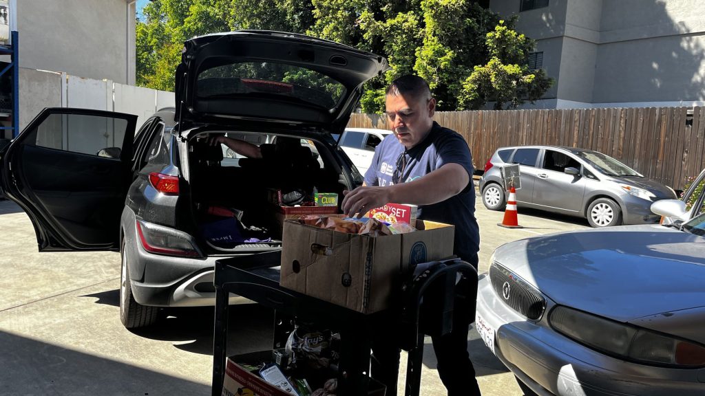 <strong>GIVING BACK</strong> — Team lead Lawrence Sanchez helps distribute boxes of food to community members in need. (Photo by Michelle Walker-Wade)