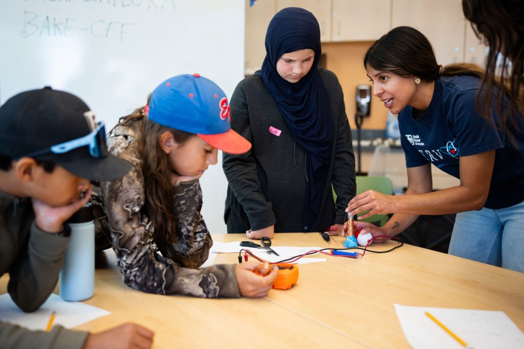 <strong>DIY WEC</strong> — Sandia engineer Raquel Valdez shows, from left, Jace Otero, Jasper Otero and Nazha Ali how to make a wave energy converter.