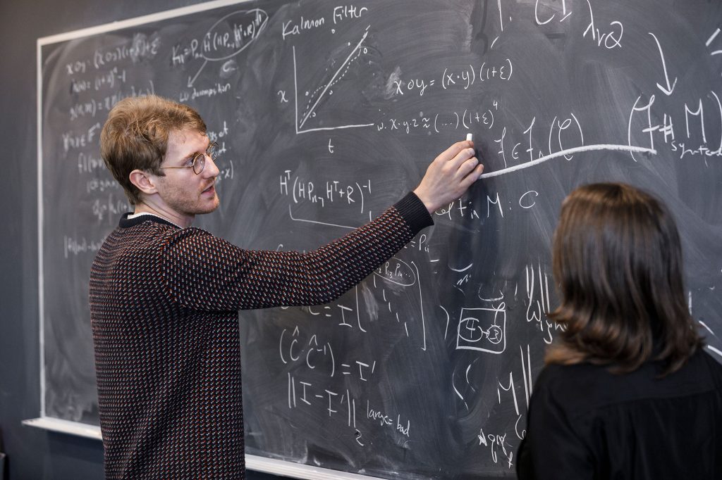 <strong>FLOATING AN IDEA</strong> — Mathematician Samuel Pollard, who formulated a way to check the basic building blocks of modern computing, describes an equation to a colleague. (Photo by Spencer Toy)