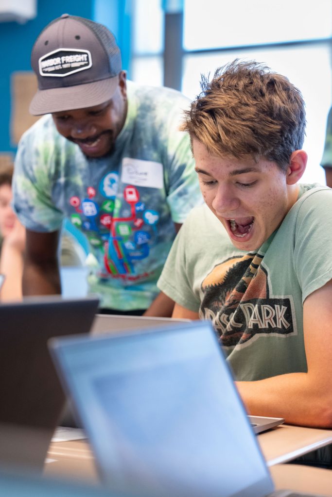 <strong>COMPUTER PROGRAMMING WOW</strong> — D’Ante Barnes left, helps a student have a “wow” moment during a cybersecurity and programming class as part of the 2026 HMTech program. (Photo by David Lienemann)