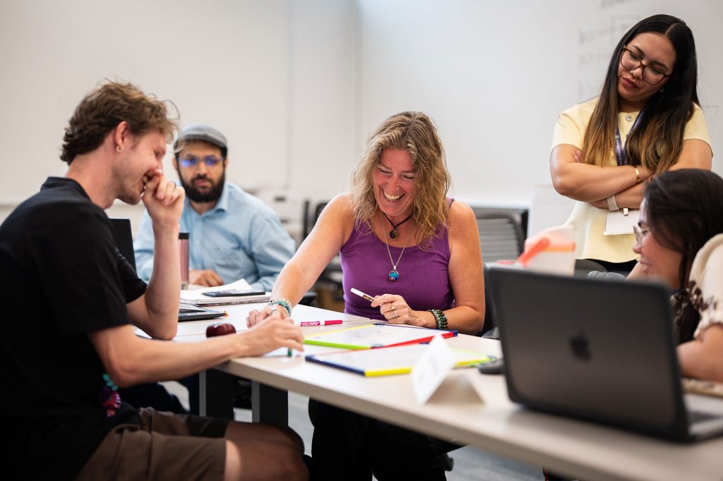 <strong>QUANTUM CONNECTIONS</strong> — QCaMP assistant instructor Jaden Brewer, left, plays Quantum Tic-Tac-Toe with teacher Brie Logan, center, as, from left, Hatem Babaa, Pejenny Rabino and Tyza Faith Iwag watch the game unfold. QCaMP offers teachers a front-row seat to quantum physics and how it continues to shape the future of computing. It is led by Sandia physicist Meagan Ivory.