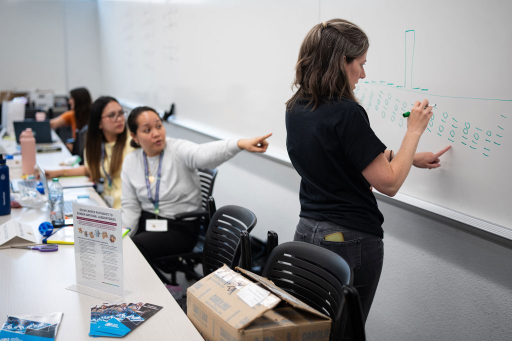 <strong>A QUANTUM FUTURE</strong> — QCaMP instructor and Sandian Meagan Ivory works through a problem on the whiteboard as she helps, from left, teachers Pejenny Rabino and Mary Grace Urciada understand quantum concepts during the weeklong workshop in June. The camp provides teachers with tools to introduce these concepts in their classrooms and increase quantum science education at an earlier stage.