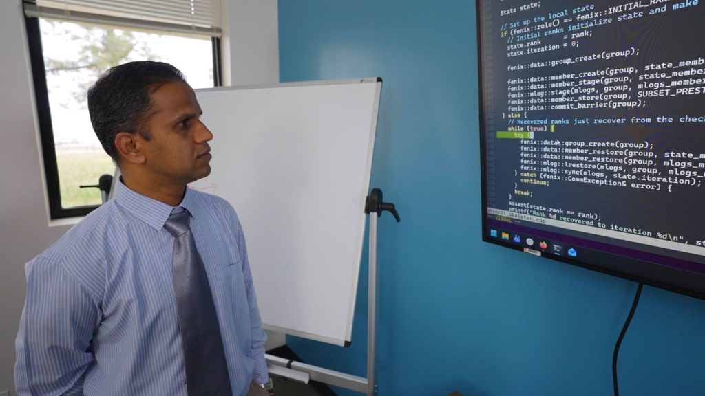 <strong>COMPUTER MONITOR</strong> — Computer scientist Hemanth Kolla studies the code for Fenix, a program he developed with Matthew Whitlock to keep small failures from bringing down whole high-performance computing systems.<br>(Photo by Bryn Whisenand)