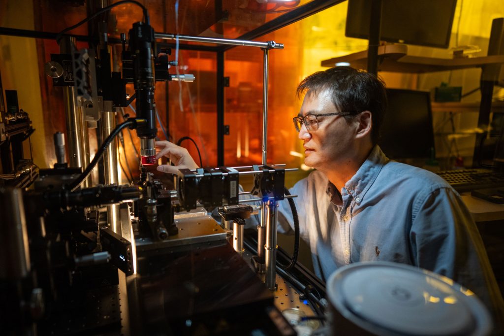 <strong>GUIDING LIGHT </strong>— Sandia scientist Jongmin Lee adjusts a machine that produces optical nanofibers 200 times thinner than a human hair. When laser beams travel through the nanofiber, halos of light form very close to it, guiding atoms along its length for quantum sensing. (Photo by Craig Fritz)