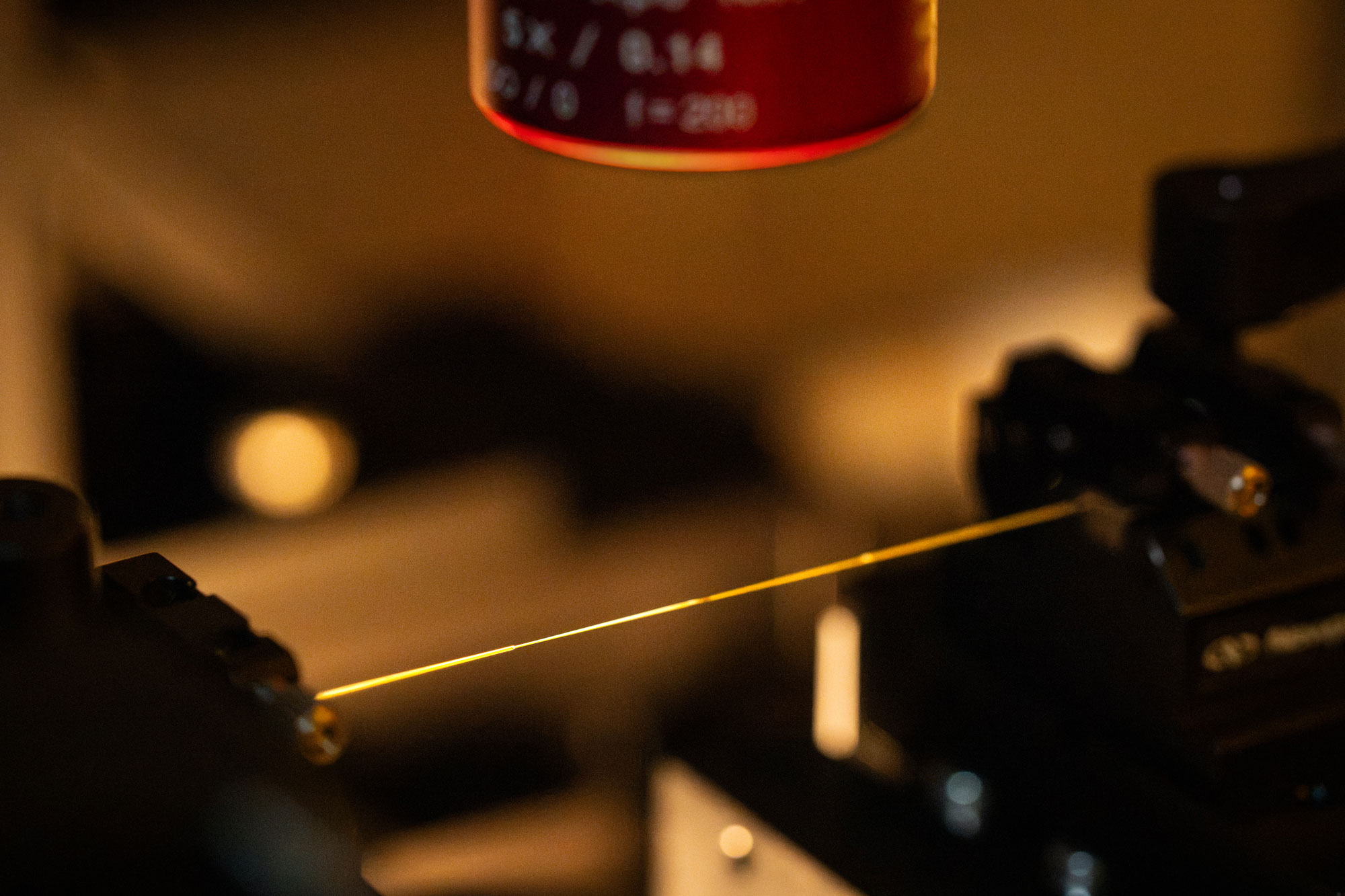 At Sandia, standard optical fiber is simultaneously heated over a flame and stretched by two motorized stages to produce an optical nanofiber. (Photo by Craig Fritz)