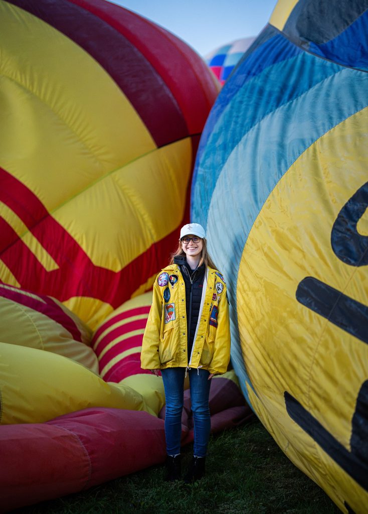 <strong>LICENSE TO FLY BEFORE A LICENSE TO DRIVE </strong>— Sandia year-round graduate intern Savannah Bradley poses with a row of Rainbow Ryders balloons. She got her pilot’s certificate before her driver’s license. That year, she was the youngest pilot to fly in Balloon Fiesta at 16. (Photo by Craig Fritz)